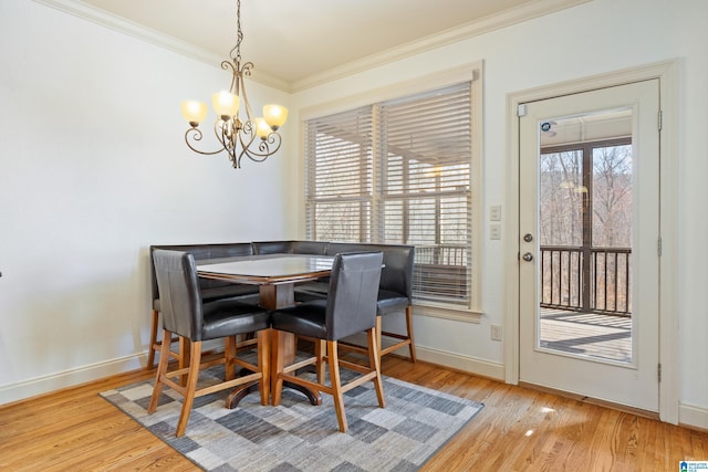 dining space with a chandelier, crown molding, baseboards, and wood finished floors