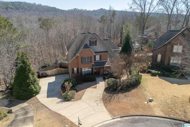 view of front facade with a forest view, brick siding, and fence