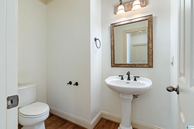 bathroom with toilet, baseboards, and wood finished floors