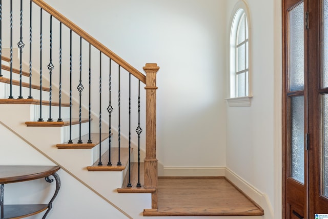 staircase with baseboards and wood finished floors