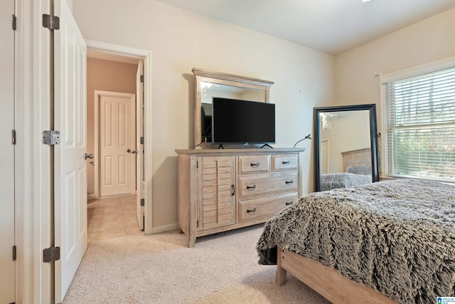 bedroom featuring light carpet and baseboards