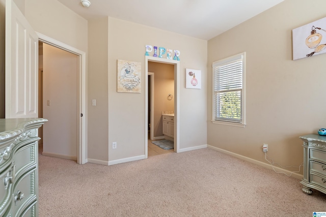 bedroom with ensuite bathroom, carpet, and baseboards