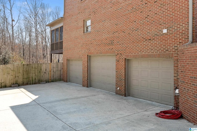 garage featuring concrete driveway and fence