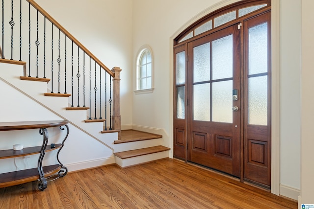 entryway with stairs, baseboards, and wood finished floors