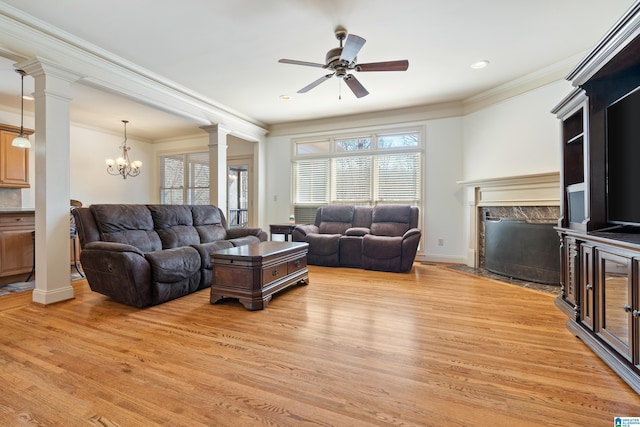 living area with a fireplace, baseboards, light wood-style floors, ornamental molding, and decorative columns