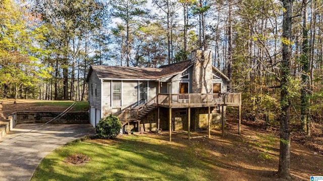 view of front of property with an attached garage, concrete driveway, stairway, a front lawn, and a chimney