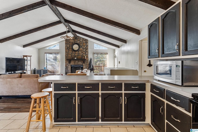 kitchen featuring a peninsula, stainless steel microwave, open floor plan, and a wealth of natural light