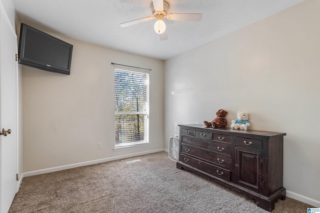 carpeted bedroom featuring a textured ceiling, a ceiling fan, and baseboards