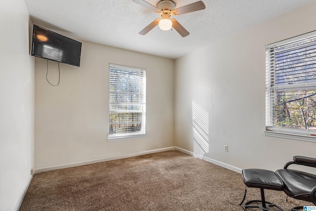 unfurnished room featuring carpet floors, ceiling fan, a textured ceiling, and baseboards