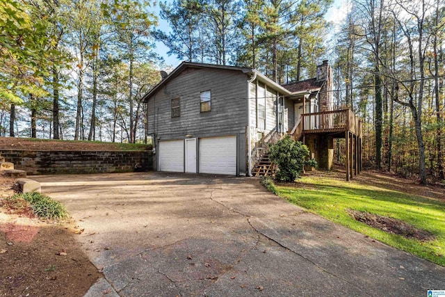 view of side of property featuring stairs, driveway, a chimney, and an attached garage