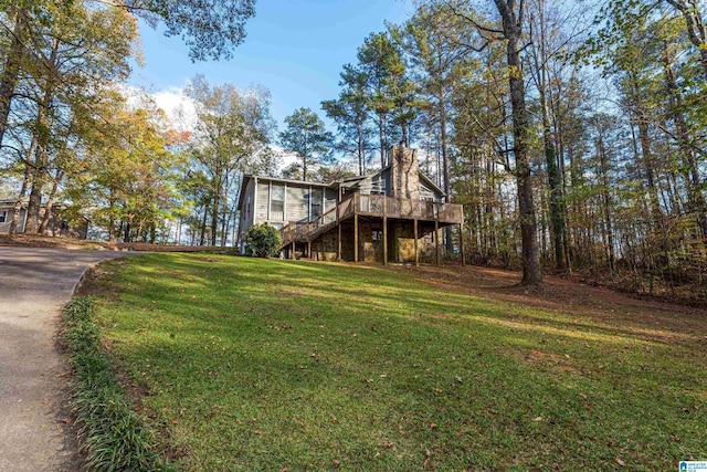 exterior space with driveway, a chimney, stairway, a deck, and a front lawn