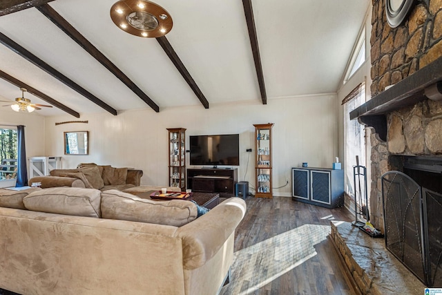 living area with vaulted ceiling with beams, a ceiling fan, a stone fireplace, wood finished floors, and baseboards