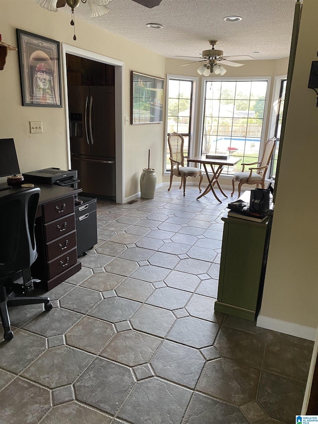 office area with ceiling fan, a textured ceiling, and baseboards