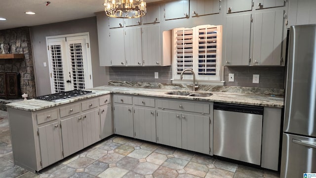 kitchen featuring a peninsula, backsplash, stainless steel appliances, and a sink