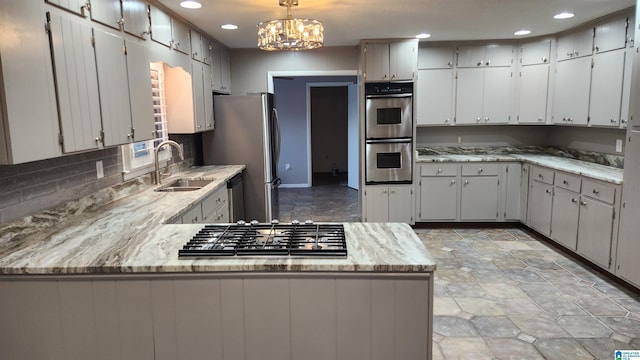 kitchen featuring tasteful backsplash, appliances with stainless steel finishes, a peninsula, a sink, and recessed lighting