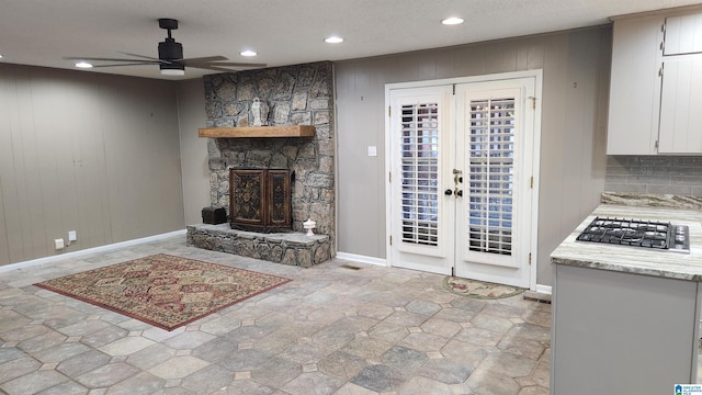 interior space with wooden walls, recessed lighting, a fireplace, a ceiling fan, and french doors