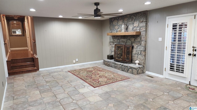 unfurnished living room with a fireplace, recessed lighting, ceiling fan, wooden walls, and baseboards