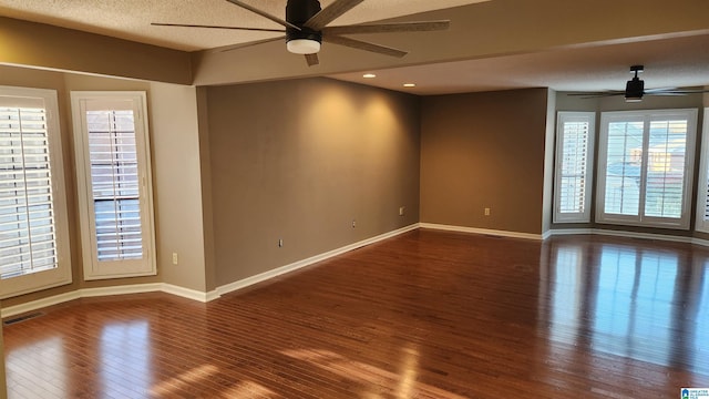 unfurnished room with a textured ceiling, wood finished floors, a ceiling fan, visible vents, and baseboards