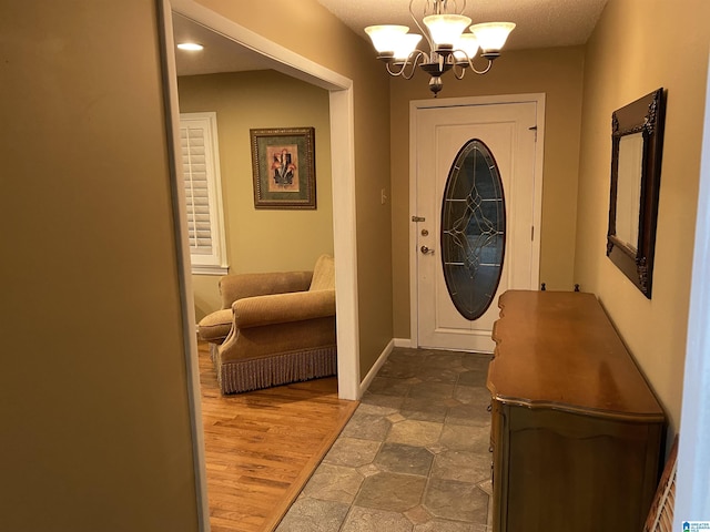 doorway to outside featuring baseboards, a chandelier, and wood finished floors