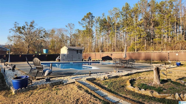 view of pool featuring a fenced in pool, an outbuilding, a storage unit, a patio area, and a fenced backyard