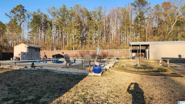 view of yard featuring a storage shed, a fenced in pool, a patio, an outbuilding, and fence