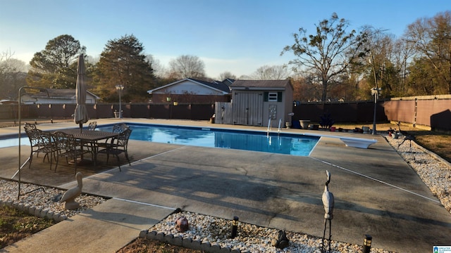 view of pool with an outbuilding, a fenced backyard, a fenced in pool, a storage unit, and a patio area