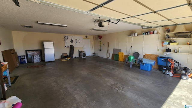 garage with a garage door opener, freestanding refrigerator, and visible vents