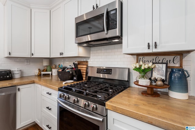 kitchen with appliances with stainless steel finishes, butcher block countertops, and white cabinetry