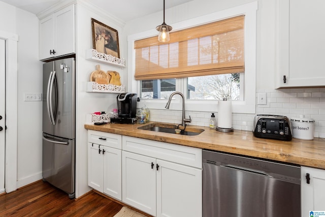 kitchen with appliances with stainless steel finishes, backsplash, butcher block countertops, and a sink