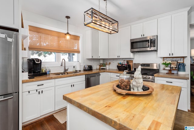 kitchen with wooden counters, appliances with stainless steel finishes, a sink, and decorative backsplash