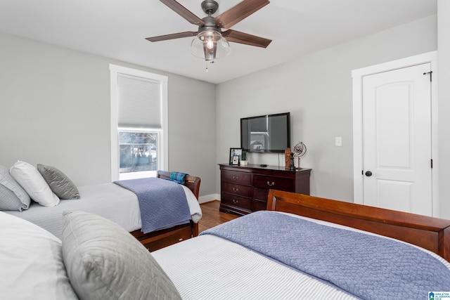 bedroom featuring dark wood-style flooring, a ceiling fan, and baseboards