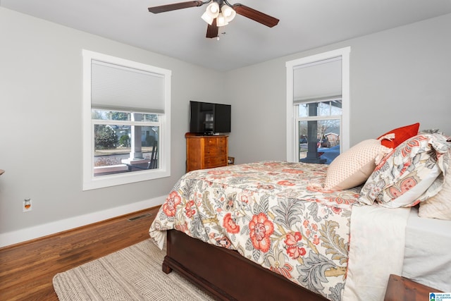 bedroom featuring a ceiling fan, baseboards, visible vents, and wood finished floors