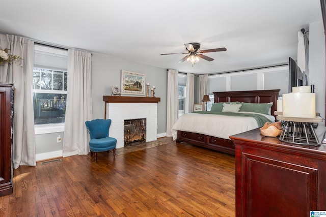 unfurnished bedroom featuring baseboards, visible vents, wood-type flooring, ceiling fan, and a fireplace