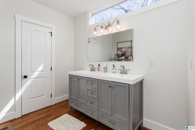 bathroom with double vanity, visible vents, a sink, and wood finished floors