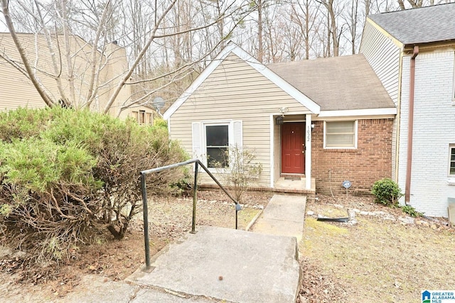 bungalow-style house with roof with shingles and brick siding