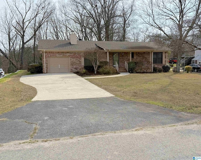 view of front facade with brick siding, a chimney, a garage, driveway, and a front lawn