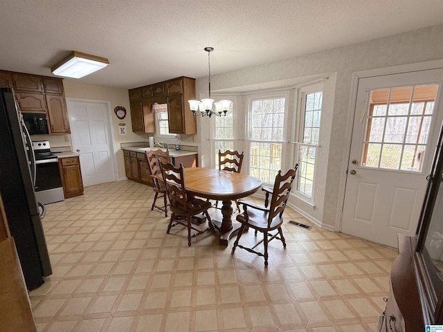 dining area featuring a chandelier, light floors, visible vents, and a healthy amount of sunlight