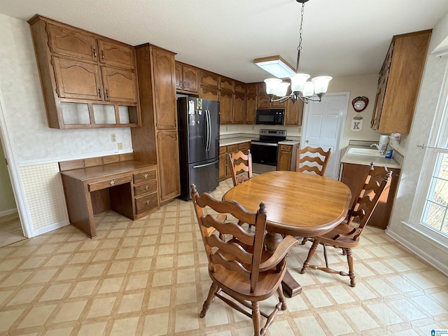 dining area with a wainscoted wall, a notable chandelier, light floors, and wallpapered walls