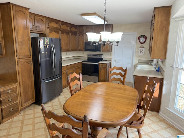 kitchen with stainless steel appliances, a chandelier, a sink, and light floors