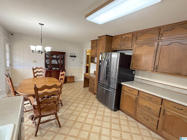 kitchen with freestanding refrigerator, brown cabinets, light floors, and wallpapered walls