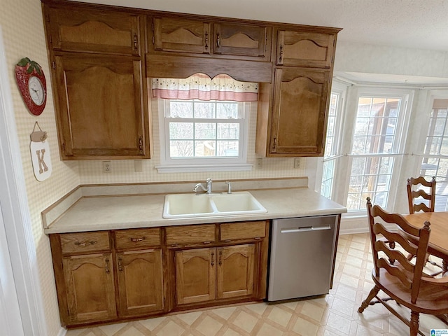 kitchen with dishwasher, light floors, a sink, and light countertops