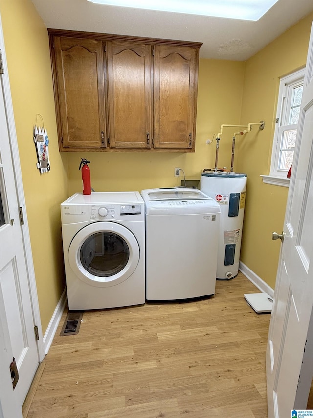 laundry area featuring cabinet space, light wood-style flooring, water heater, and washer and dryer