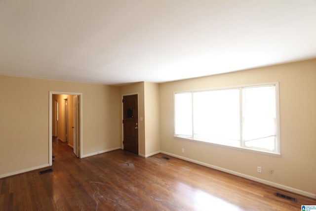 empty room with visible vents, baseboards, and wood finished floors