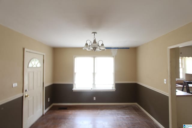 foyer entrance featuring dark wood-type flooring, baseboards, and an inviting chandelier