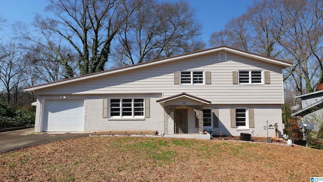 view of front facade featuring a front yard, brick siding, driveway, and an attached garage