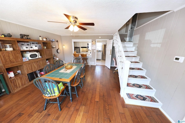 dining area featuring stairs, a textured ceiling, hardwood / wood-style flooring, and a ceiling fan