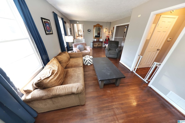 living area with a textured ceiling, wood-type flooring, and baseboards