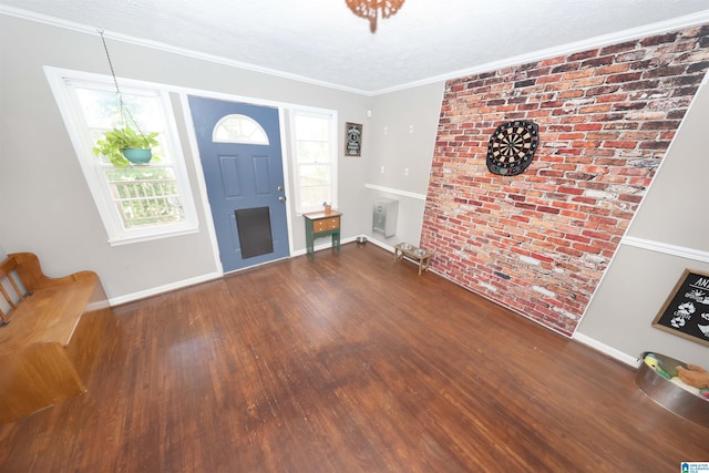 entrance foyer featuring ornamental molding, baseboards, brick wall, and wood finished floors