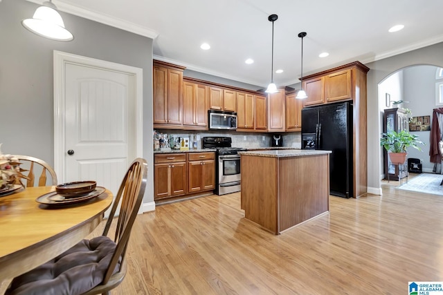 kitchen with light wood finished floors, arched walkways, brown cabinetry, stainless steel appliances, and crown molding