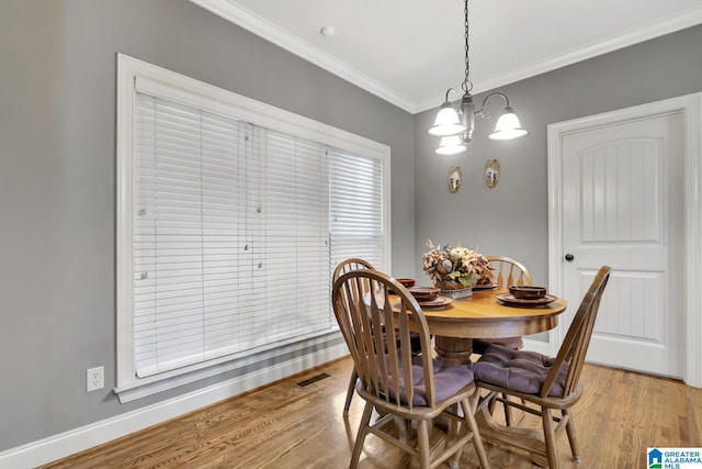 dining room with light wood-style floors, baseboards, visible vents, and crown molding